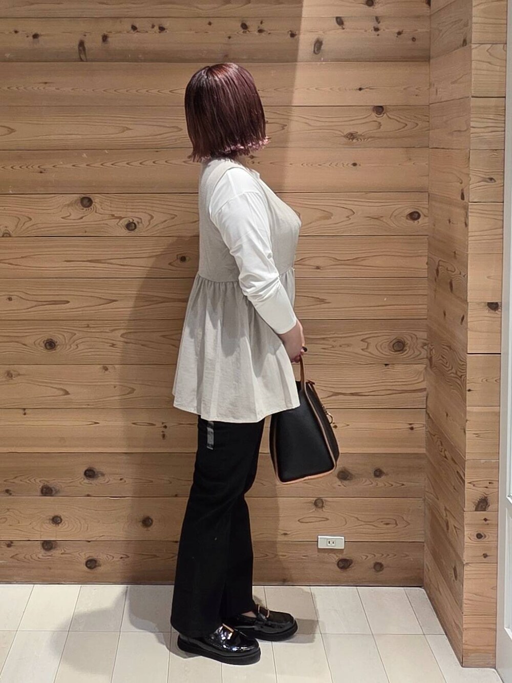 ブラック系のローファー、ブラック系のデニムパンツ、ベージュ系のベストを着用したレディースの秋コーディネートの2枚目の写真