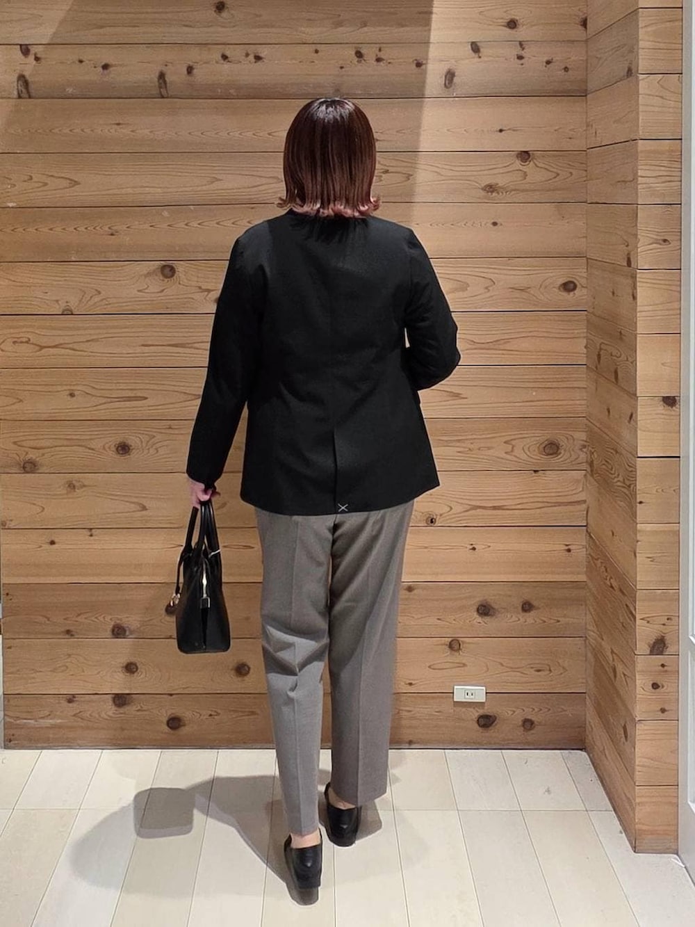 ブラック系のローファー、ブラック系のショルダーバッグ、ブラウン系のスラックスを着用したレディースの冬コーディネートの3枚目の写真