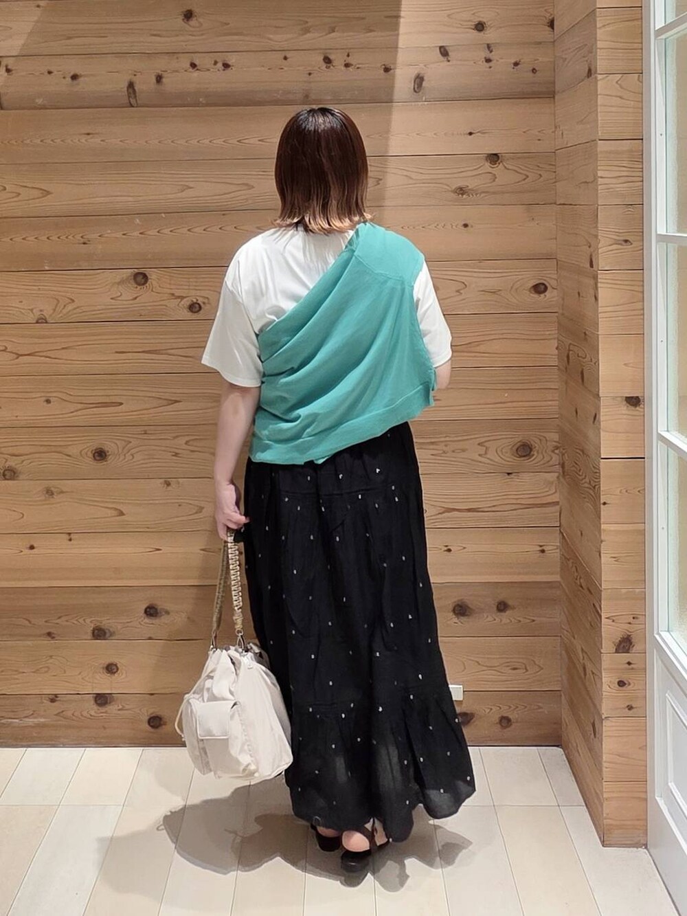 ブラック系のスカート、ホワイト系のTシャツ/カットソー、グリーン系のカーディガン/ボレロを着用したレディースの夏コーディネートの3枚目の写真