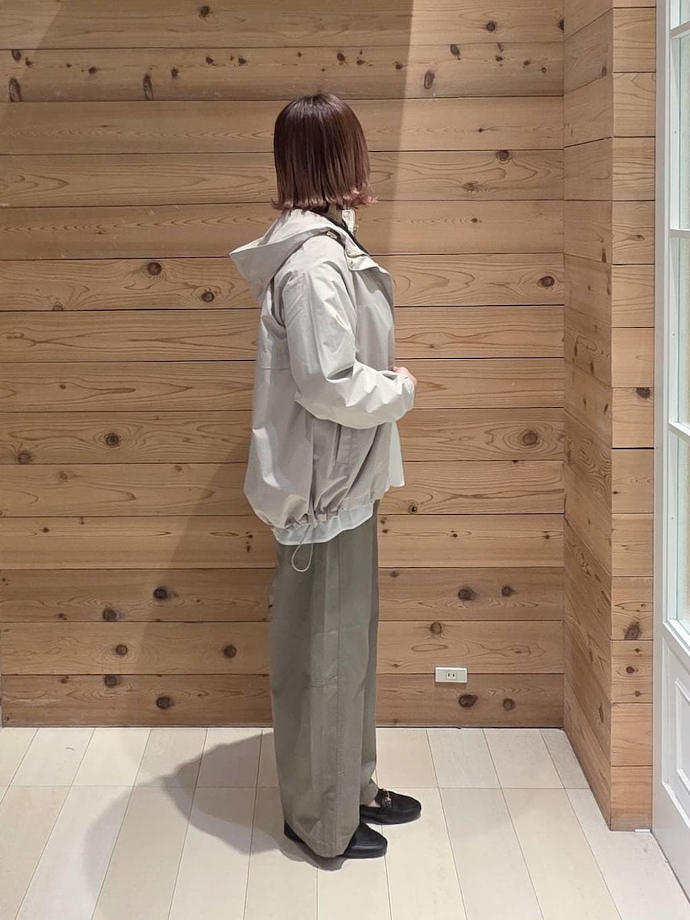 ブラック系のローファー、ホワイト系のショルダーバッグ、ベージュ系のマウンテンパーカーを着用したレディースの春コーディネートの2枚目の写真