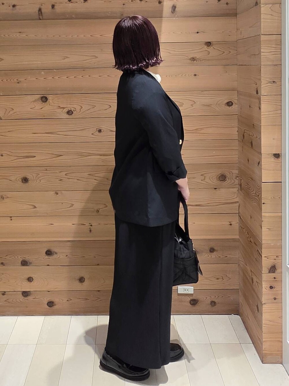 ブラック系のローファー、ブラック系のトートバッグ、ブラック系のスカートを着用したレディースの秋コーディネートの2枚目の写真