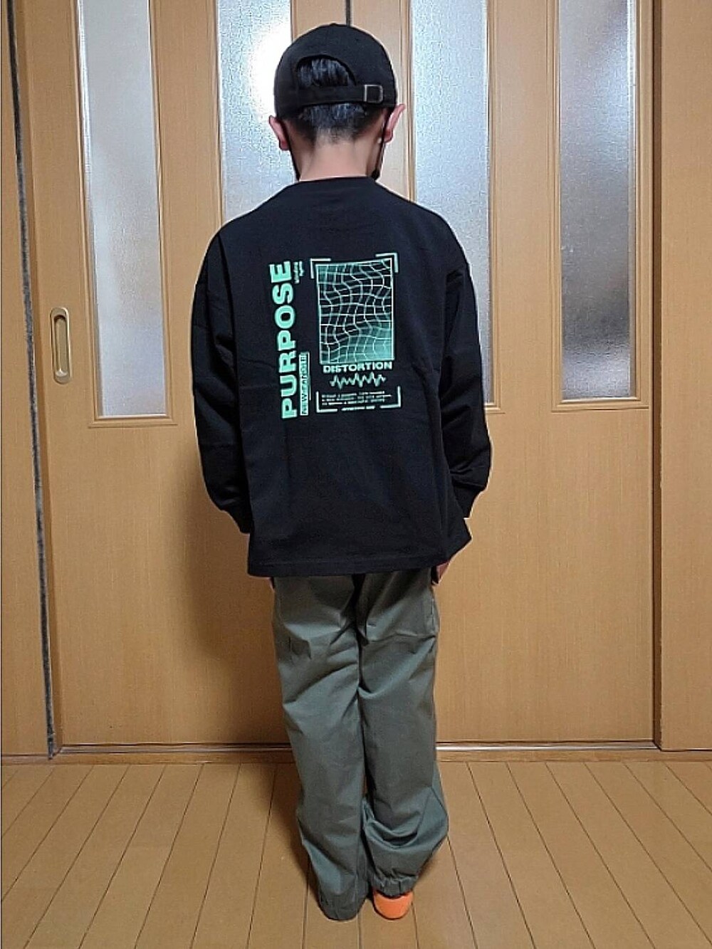 グリーン系のカーゴパンツ、ブラック系のTシャツ/カットソー、ブラック系のキャップを着用したキッズの秋コーディネートの3枚目の写真