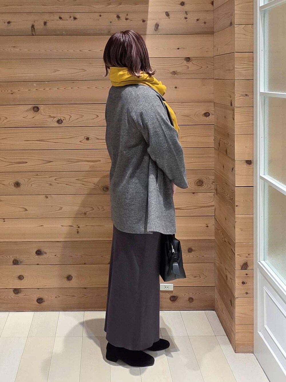 ブラック系のボストンバッグ、グレー系のチェスターコート、グレー系のワンピースを着用したレディースの冬コーディネートの2枚目の写真