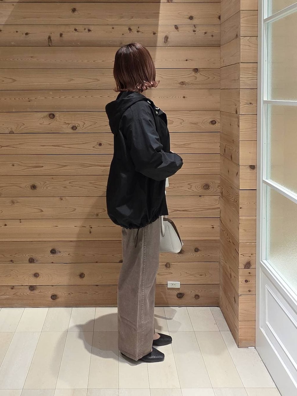 ブラック系のパンプス、ホワイト系のショルダーバッグ、ブラック系のマウンテンパーカーを着用したレディースの春コーディネートの2枚目の写真