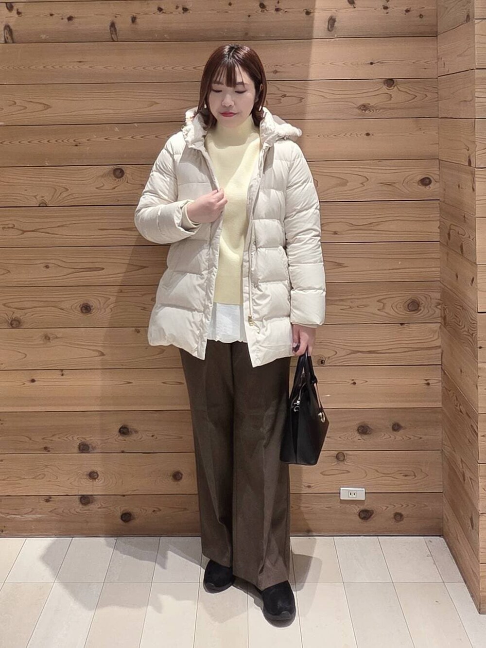 ブラック系のショルダーバッグ、ベージュ系のダウンジャケット/コート、ブラック系のブーツを着用したレディースの冬コーディネートの4枚目の写真