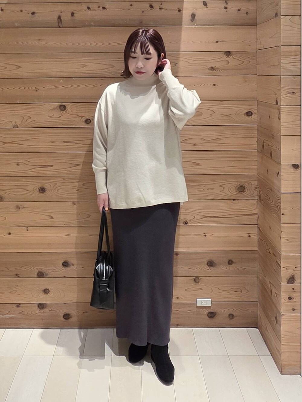 ブラック系のボストンバッグ、グレー系のチェスターコート、グレー系のワンピースを着用したレディースの冬コーディネートの4枚目の写真