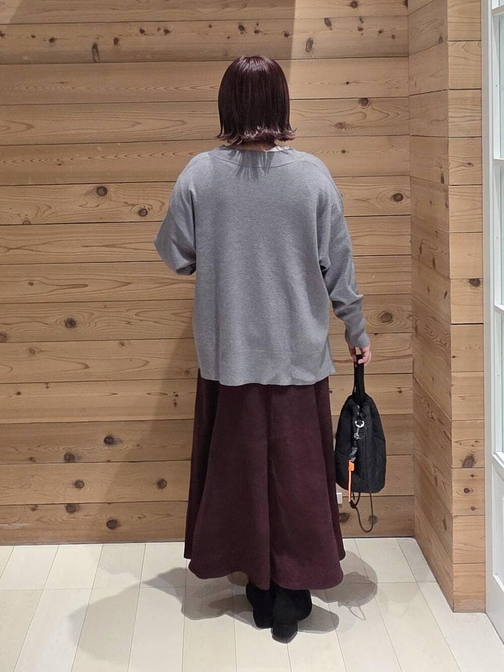 ブラウン系のチェスターコート、レッド系のスカート、ブラック系のハンドバッグを着用したレディースの冬コーディネートの3枚目の写真