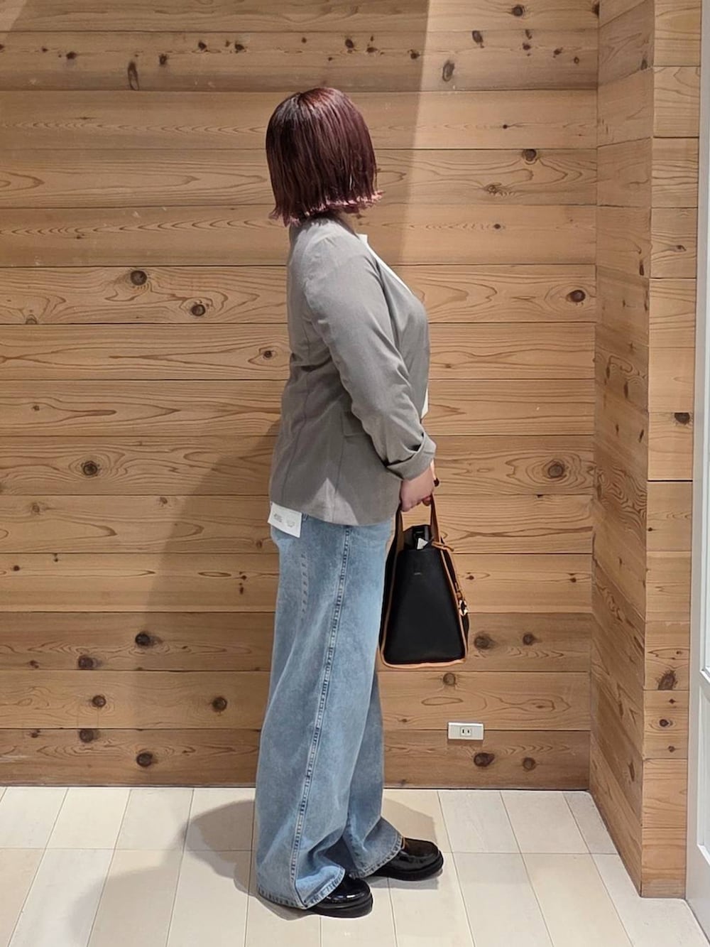 ブラウン系のノーカラージャケット、ブラック系のローファー、ブルー系のデニムパンツを着用したレディースの秋コーディネートの2枚目の写真