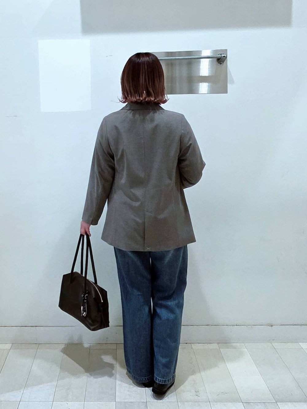 ブラック系のローファー、ブラウン系のボストンバッグ、ブルー系のデニムパンツを着用したレディースの春コーディネートの3枚目の写真