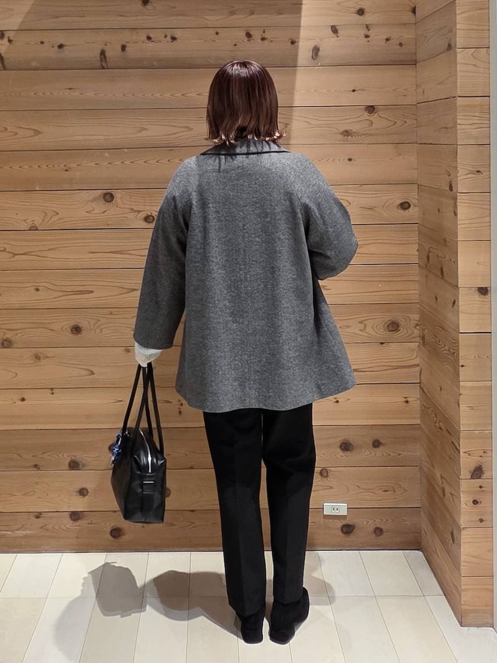 ブラック系のボストンバッグ、グレー系のチェスターコート、ブラック系のその他パンツを着用したレディースの冬コーディネートの3枚目の写真