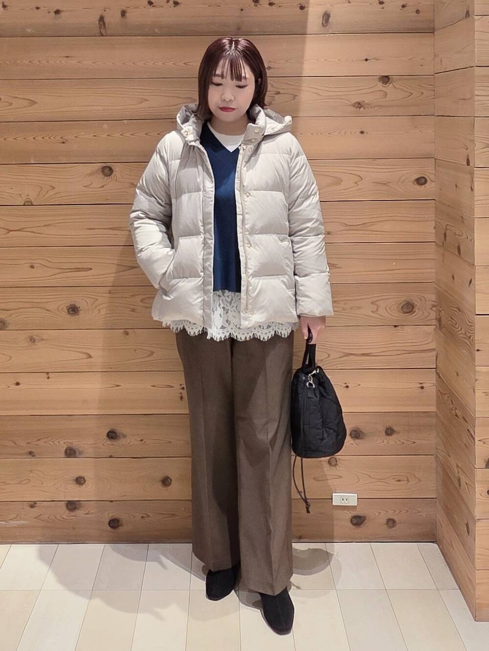 ベージュ系のダウンジャケット/コート、ブラック系のハンドバッグ、ブルー系のニット/セーターを着用したレディースの冬コーディネートの4枚目の写真