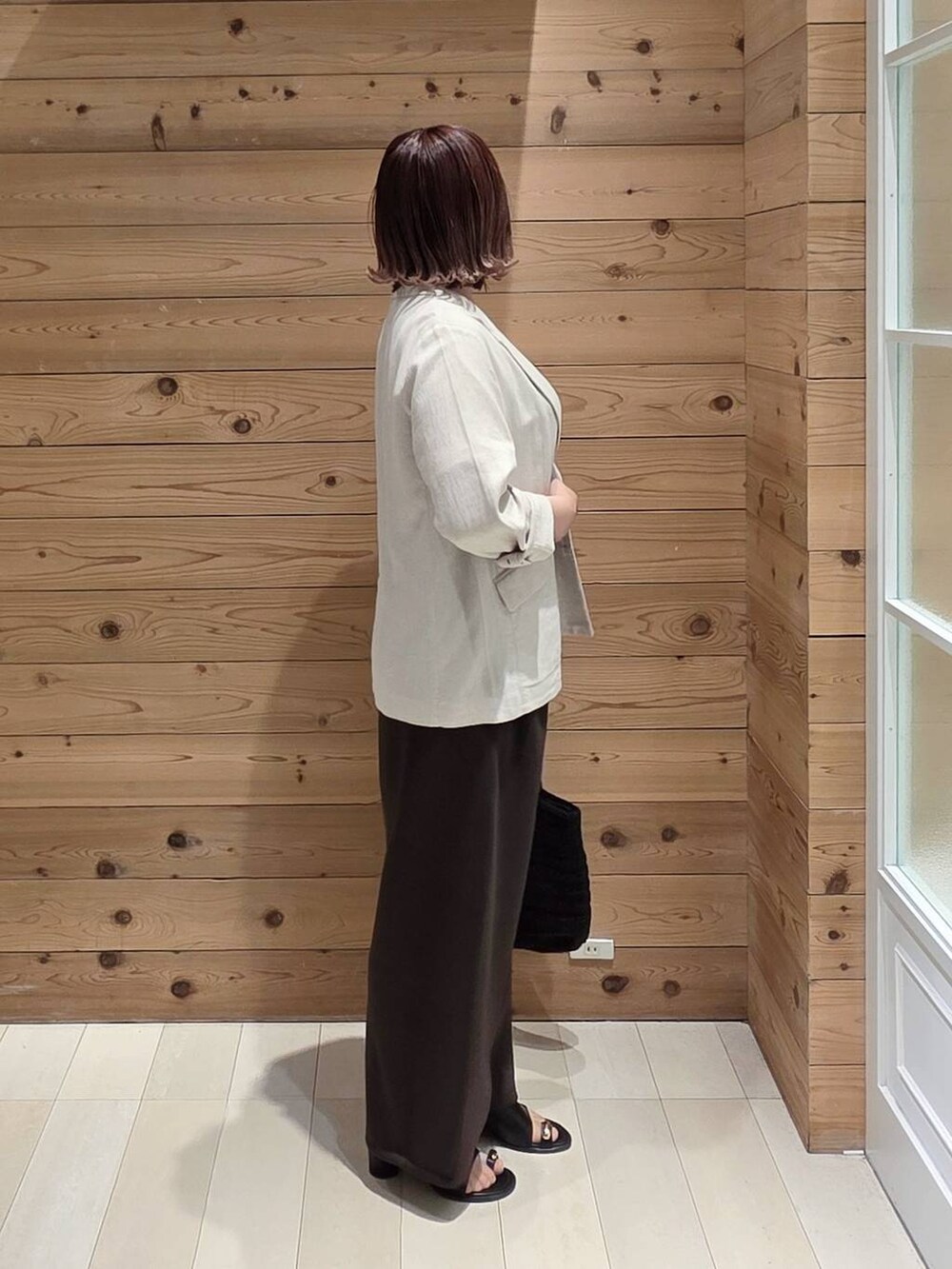 ベージュ系のテーラードジャケット、ホワイト系のTシャツ/カットソー、ブラック系のクラッチバッグを着用したレディースの春コーディネートの2枚目の写真