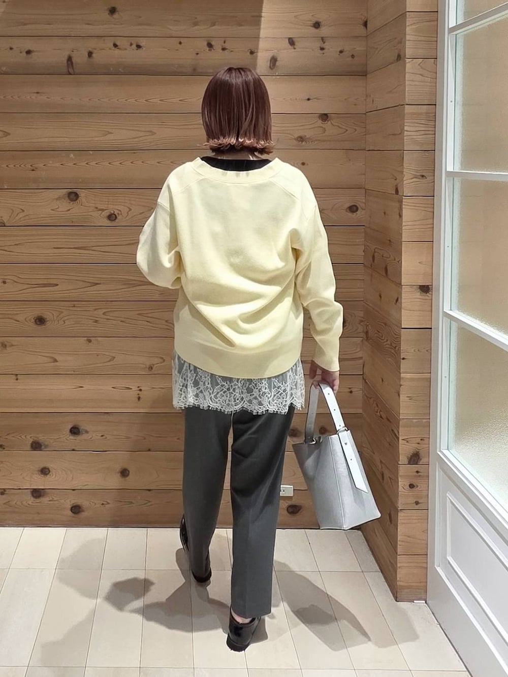 ブラック系のローファー、シルバー系のショルダーバッグ、グレー系のスラックスを着用したレディースの春コーディネートの3枚目の写真