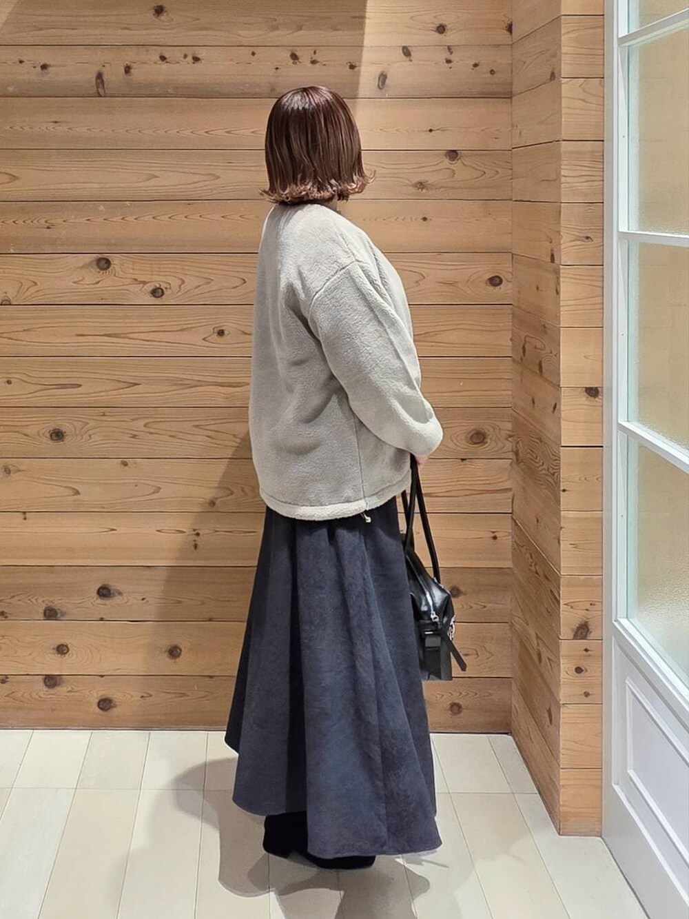 ブラック系のボストンバッグ、ブラウン系のブルゾン、グレー系のスカートを着用したレディースの冬コーディネートの2枚目の写真