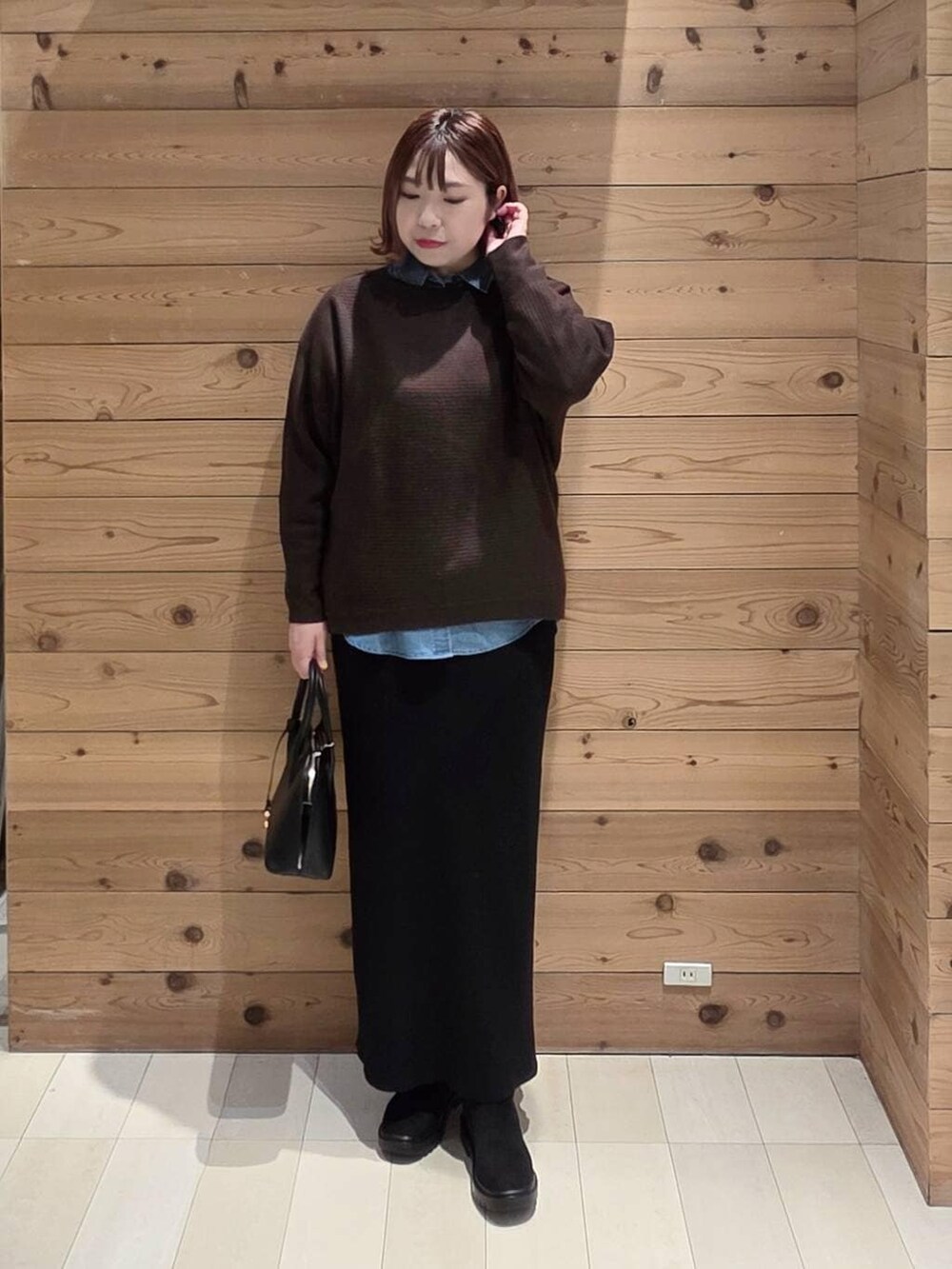 ブラック系のショルダーバッグ、ブラウン系のチェスターコート、ブルー系のシャツ/ブラウスを着用したレディースの冬コーディネートの4枚目の写真