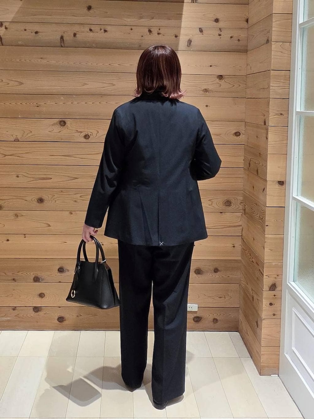 ブラック系のローファー、ブラック系のショルダーバッグ、ブルー系のスラックスを着用したレディースの春コーディネートの3枚目の写真