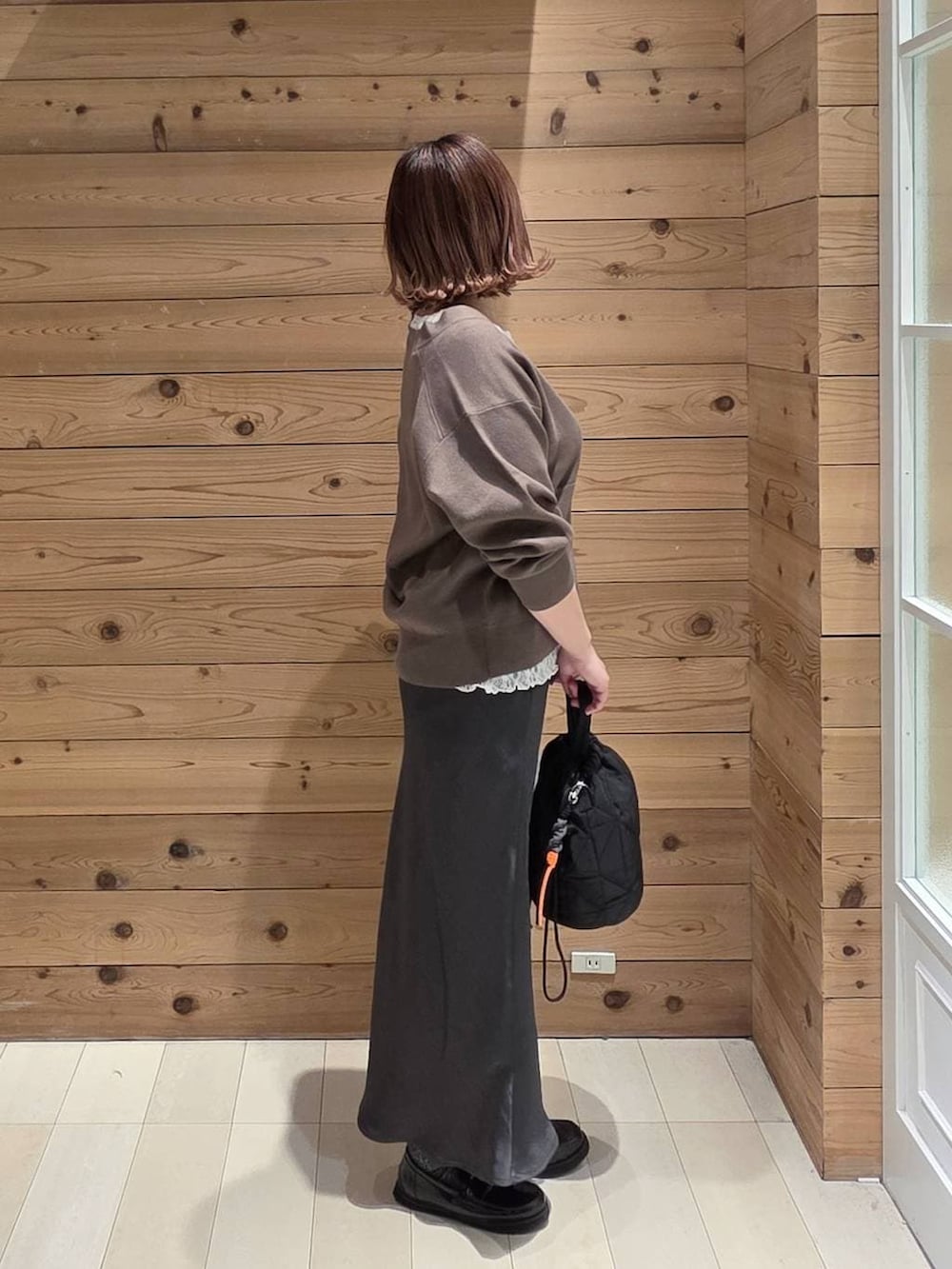 ブラック系のローファー、ブラック系のハンドバッグ、ホワイト系のパーカーを着用したレディースの春コーディネートの2枚目の写真