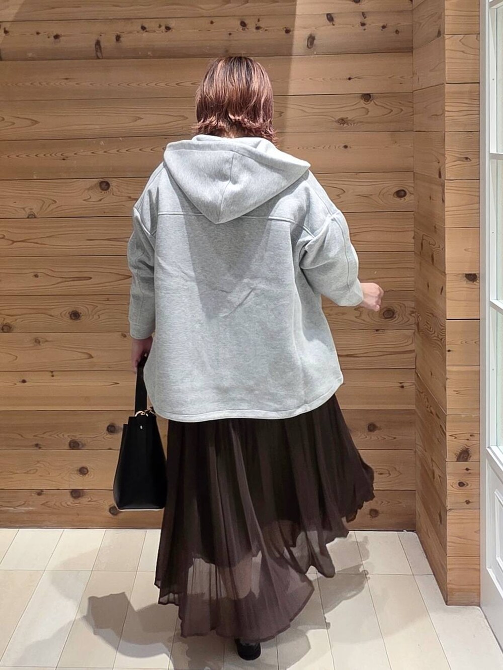 ブラック系のローファー、ブラック系のショルダーバッグ、ブラウン系のスカートを着用したレディースの秋コーディネートの3枚目の写真