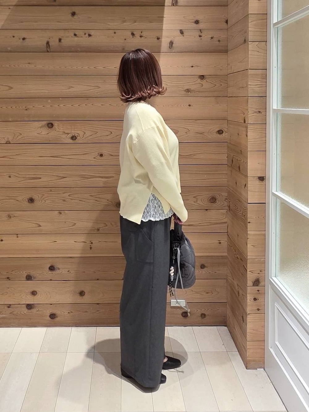 ブラック系のパンプス、グレー系のハンドバッグ、イエロー系のニット/セーターを着用したレディースの春コーディネートの2枚目の写真