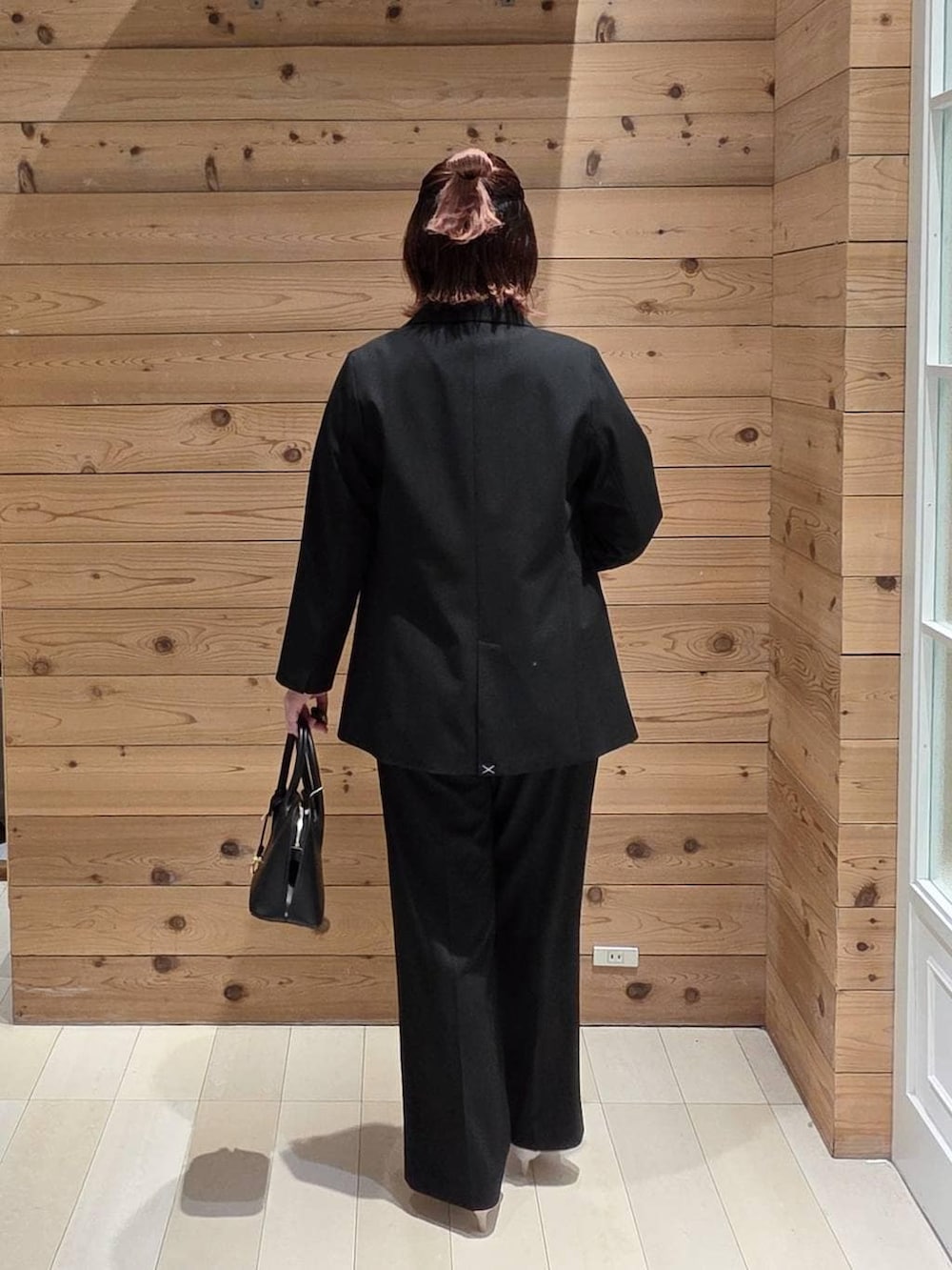 ブラック系のショルダーバッグ、ホワイト系のパンプス、ブラック系のスラックスを着用したレディースの冬コーディネートの3枚目の写真