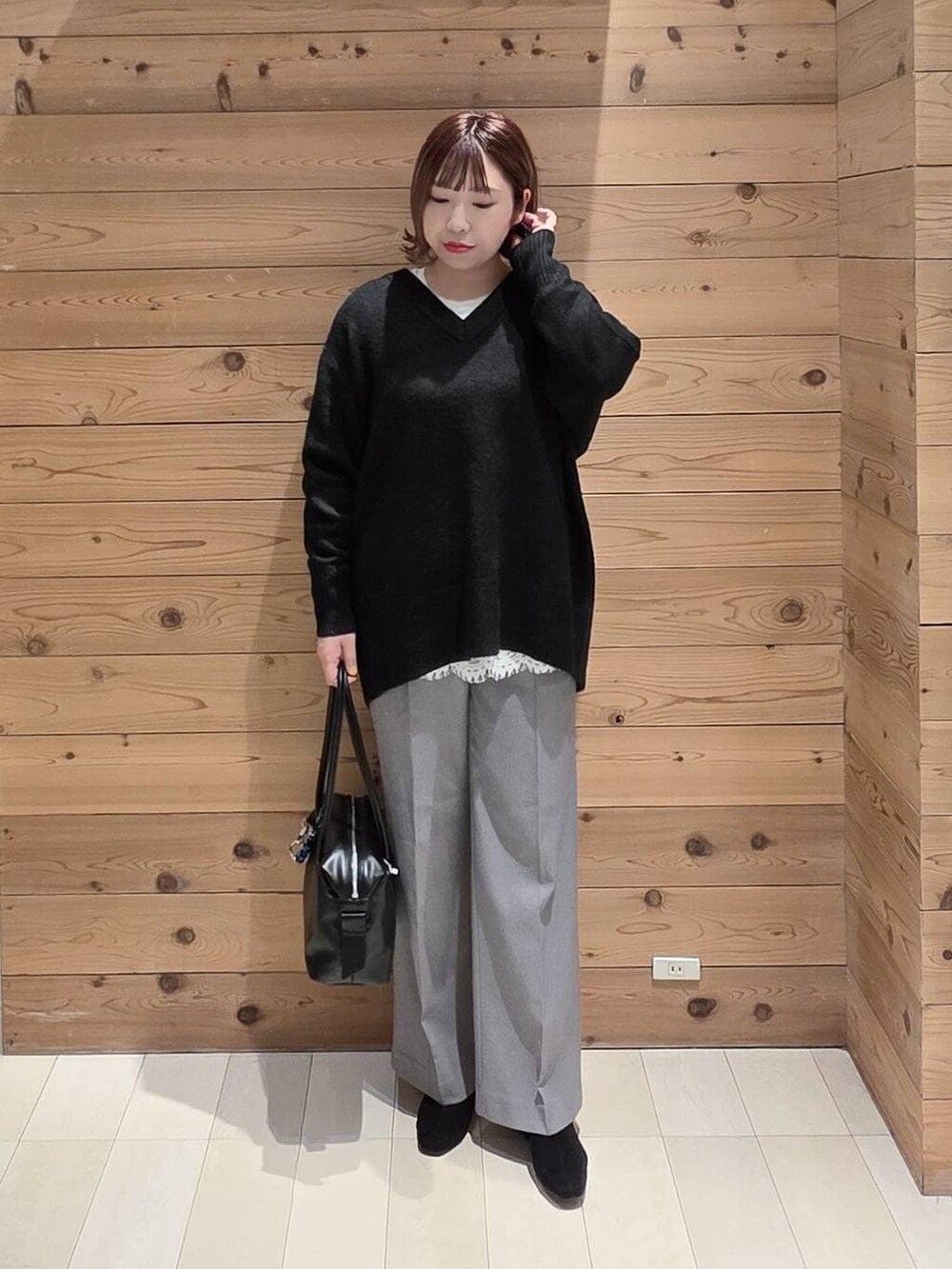 ブラック系のボストンバッグ、グレー系のチェスターコート、ブラック系のニット/セーターを着用したレディースの冬コーディネートの4枚目の写真