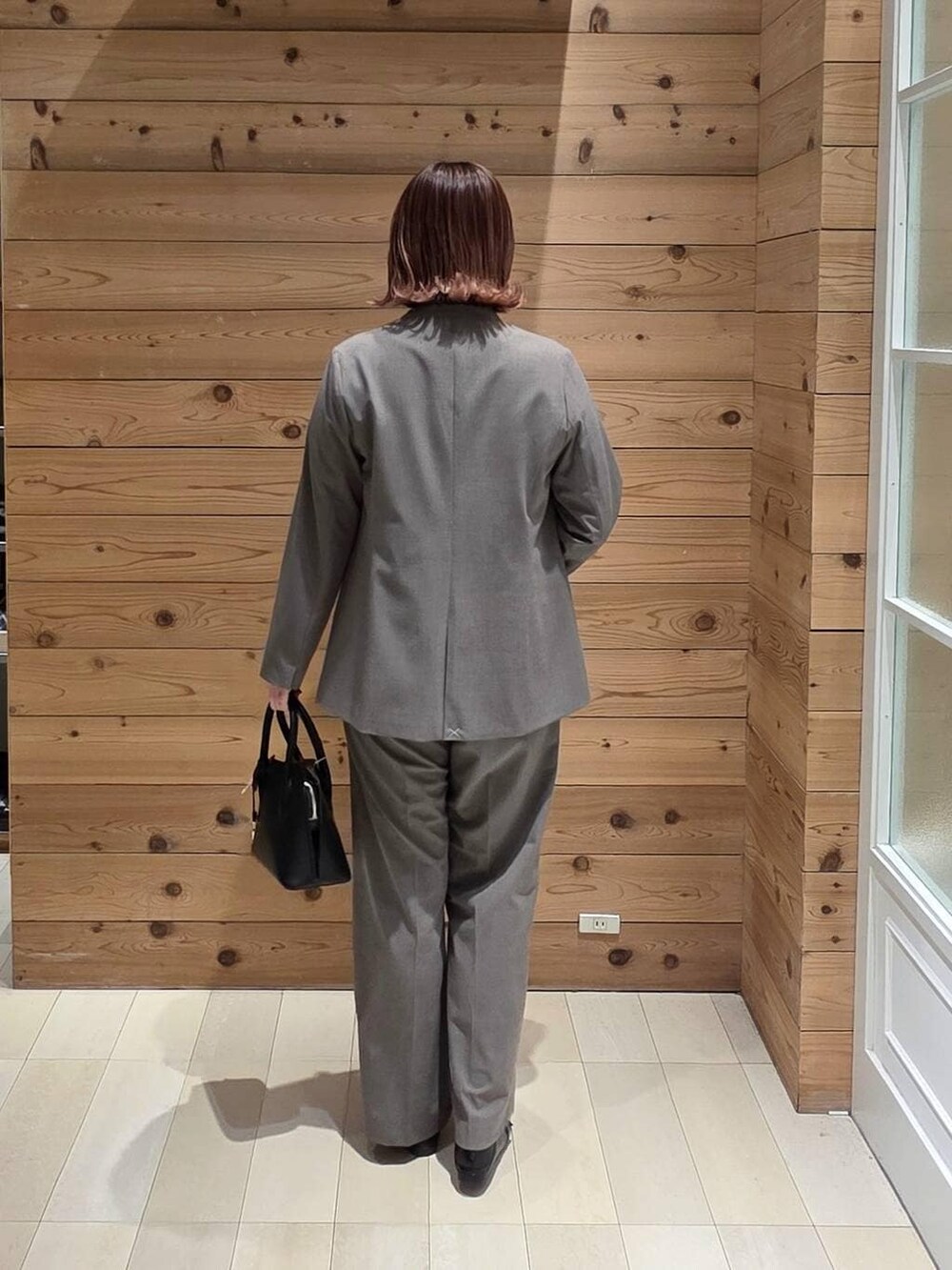 ブラック系のローファー、ブラック系のショルダーバッグ、ブラウン系のスラックスを着用したレディースの春コーディネートの3枚目の写真