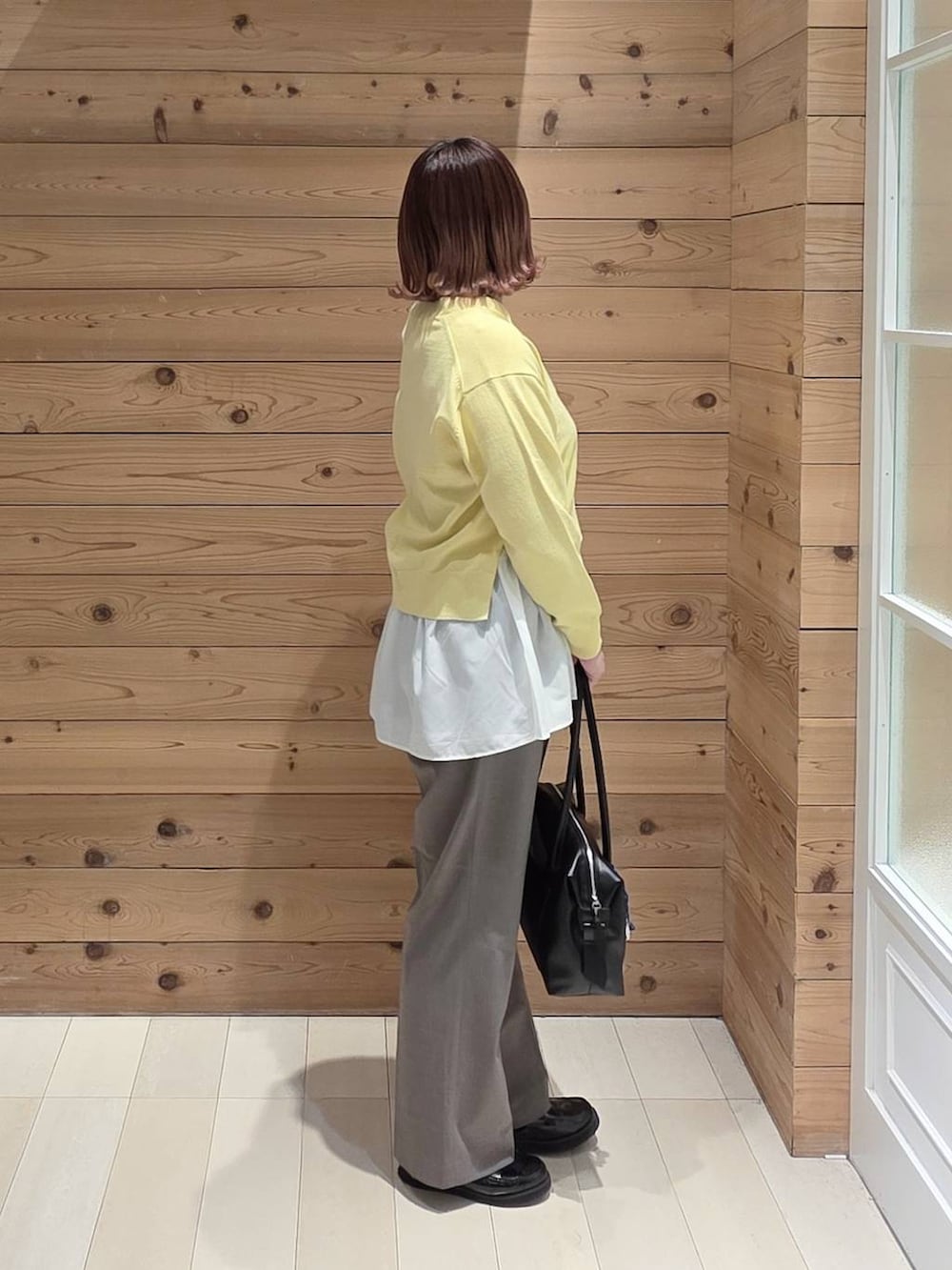 ブラック系のローファー、ブラック系のボストンバッグ、ブラウン系のスラックスを着用したレディースの春コーディネートの2枚目の写真