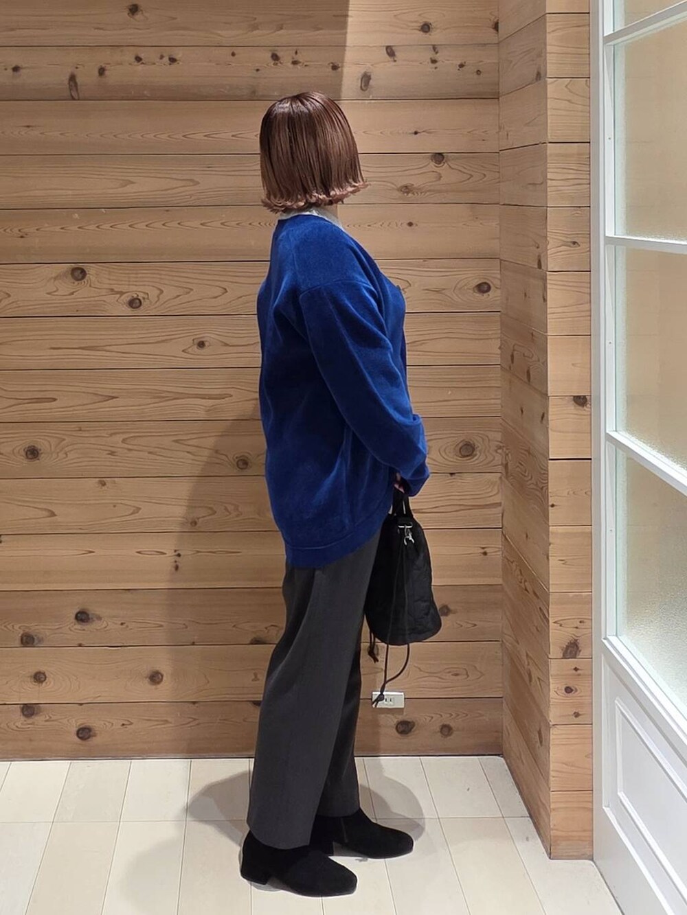 ブラウン系のチェスターコート、グレー系のニット/セーター、グレー系のその他パンツを着用したレディースの秋コーディネートの2枚目の写真