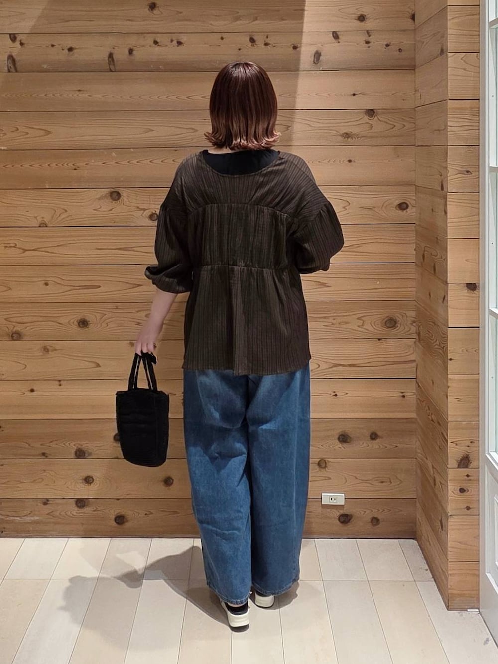 ブルー系のデニムパンツ、ブラック系のタンクトップ、ブラック系のクラッチバッグを着用したレディースの春コーディネートの3枚目の写真