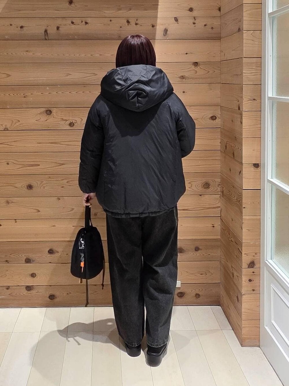 ブラック系のダウンジャケット/コート、ブラック系のデニムパンツ、ブラック系のハンドバッグを着用したレディースの冬コーディネートの3枚目の写真