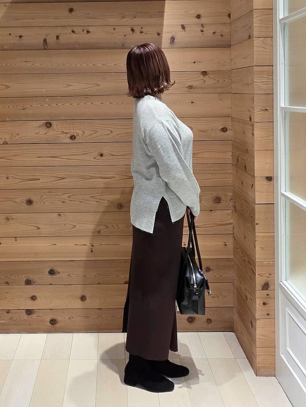 グレー系のブルゾン、ブラック系のボストンバッグ、シルバー系のニット/セーターを着用したレディースの冬コーディネートの2枚目の写真