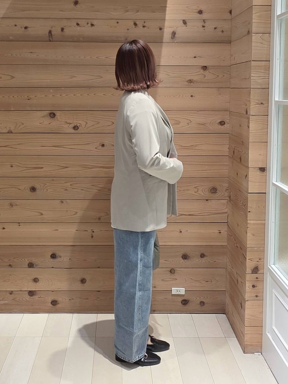 ブラック系のローファー、グリーン系のハンドバッグ、ベージュ系のテーラードジャケットを着用したレディースの春コーディネートの2枚目の写真