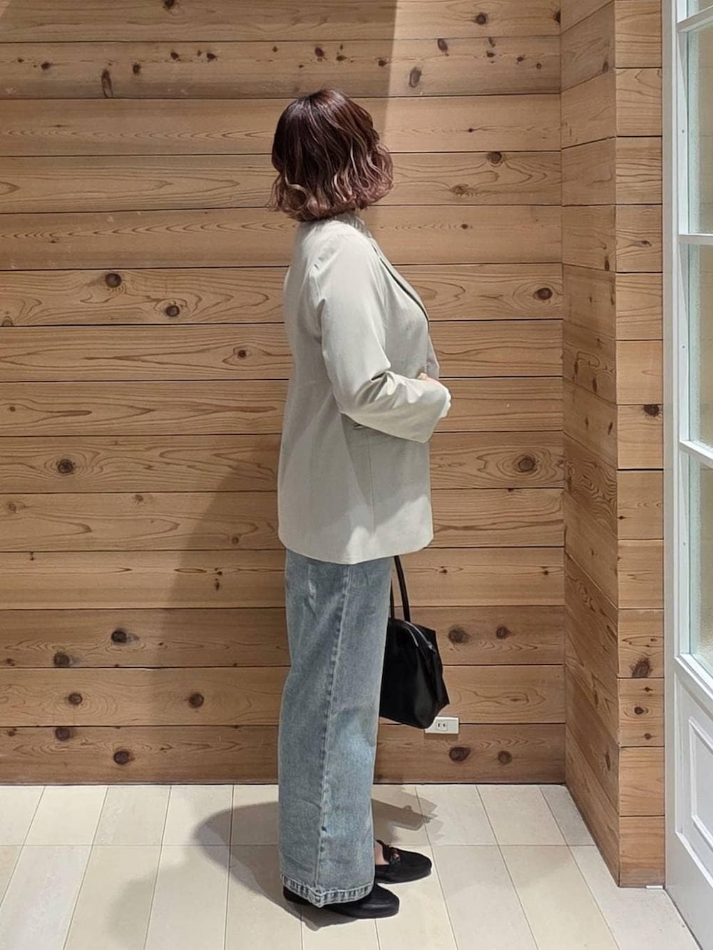 ブラック系のローファー、ブラック系のボストンバッグ、ブルー系のデニムパンツを着用したレディースの春コーディネートの2枚目の写真