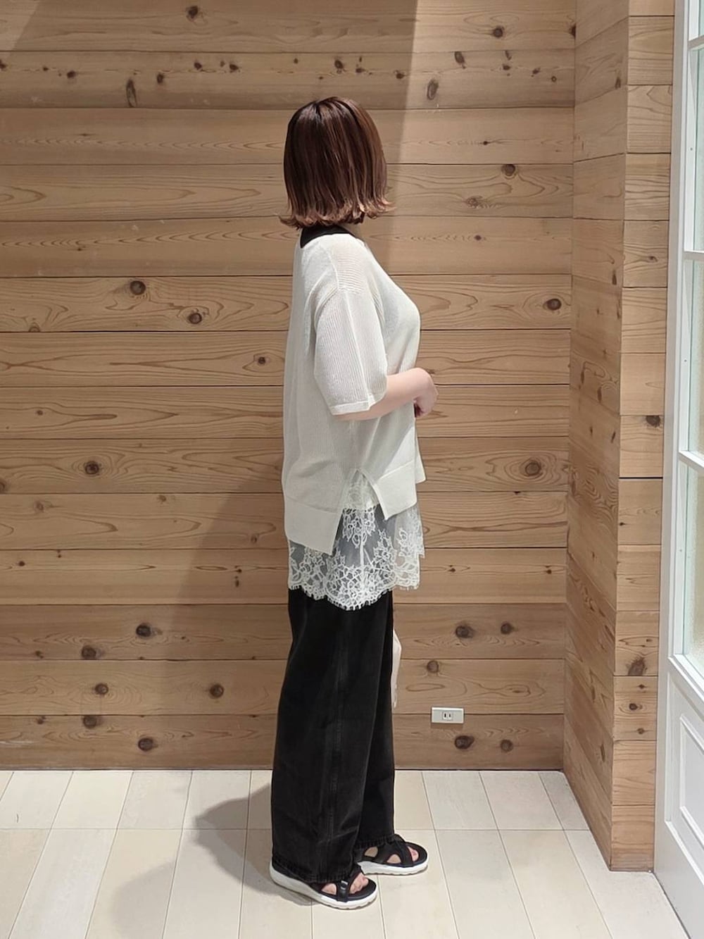 ブラック系のデニムパンツ、ブラック系のタンクトップ、ホワイト系のキャミソールを着用したレディースの夏コーディネートの2枚目の写真