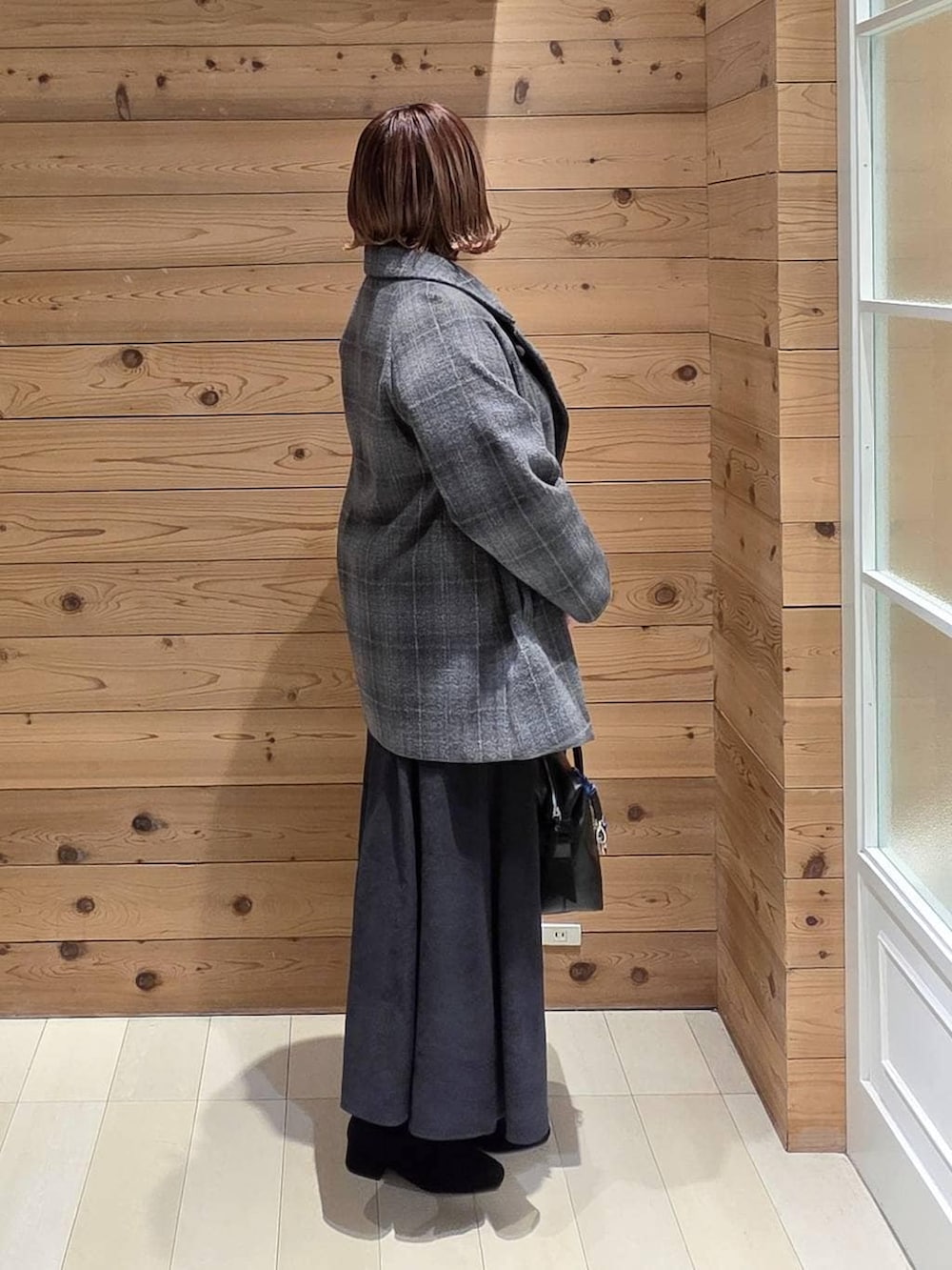 ブラック系のボストンバッグ、その他のチェスターコート、グレー系のスカートを着用したレディースの冬コーディネートの2枚目の写真