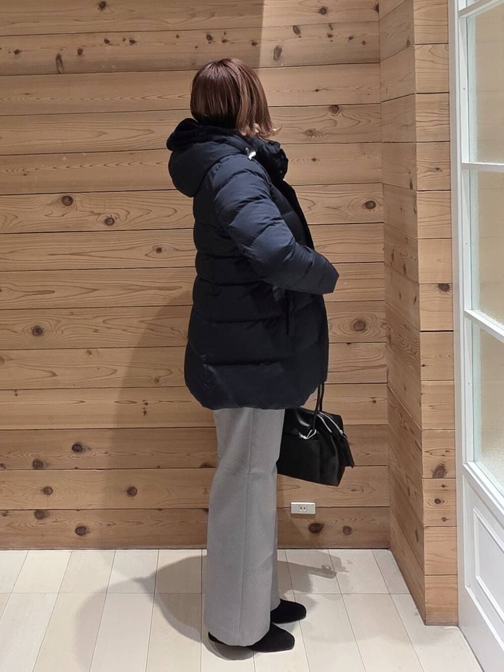 ブラック系のボストンバッグ、ブルー系のダウンジャケット/コート、グレー系のその他パンツを着用したレディースの冬コーディネートの2枚目の写真