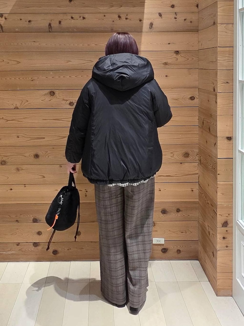 ブラック系のダウンジャケット/コート、ブラック系のハンドバッグ、ホワイト系のTシャツ/カットソーを着用したレディースの冬コーディネートの3枚目の写真