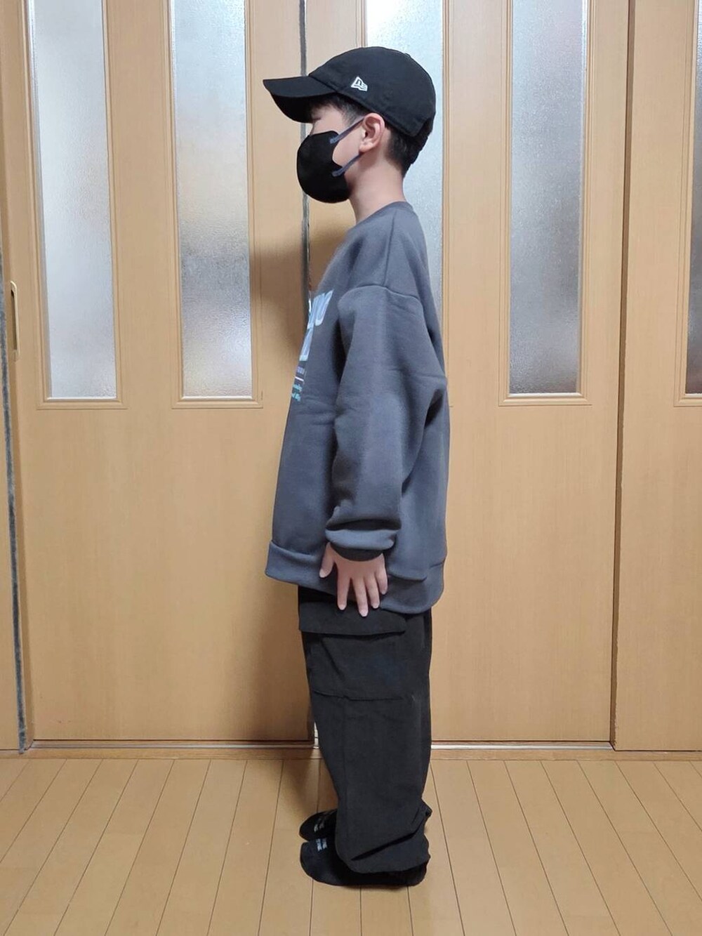 ベージュ系のブルゾン、ブラック系のカーゴパンツ、グレー系のスウェットを着用したキッズの冬コーディネートの2枚目の写真