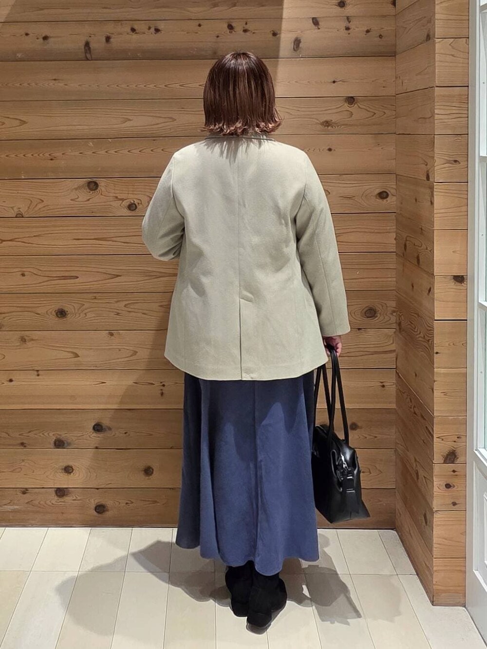 ブラック系のボストンバッグ、ブルー系のスカート、グレー系のニット/セーターを着用したレディースの冬コーディネートの3枚目の写真