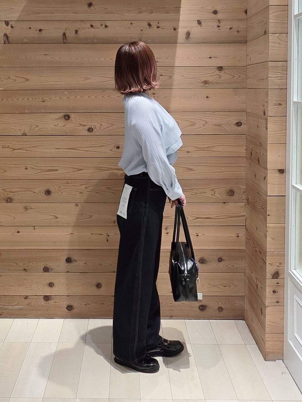 ブラック系のローファー、ブラック系のボストンバッグ、ブルー系のデニムパンツを着用したレディースの春コーディネートの3枚目の写真