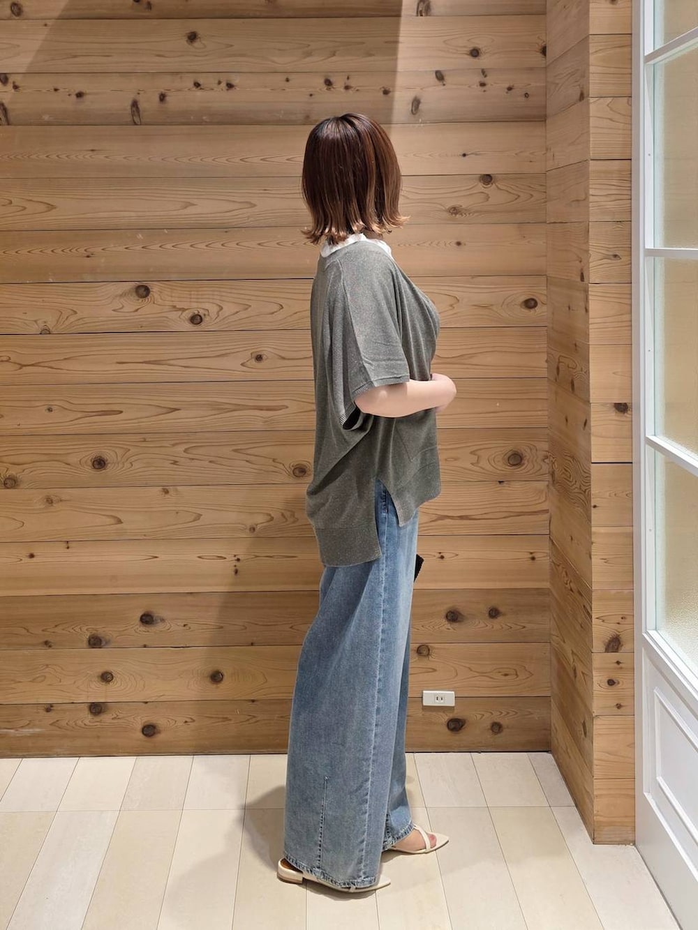 ブラウン系のカーディガン/ボレロ、ブルー系のデニムパンツ、ブラック系のクラッチバッグを着用したレディースの夏コーディネートの2枚目の写真