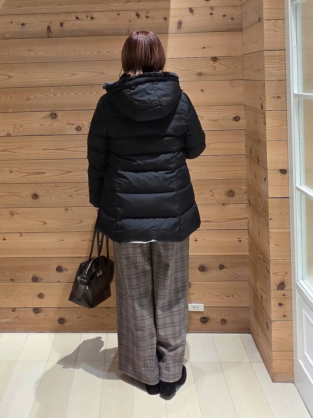 ブラウン系のボストンバッグ、ブラック系のダウンジャケット/コート、ベージュ系のスウェットを着用したレディースの冬コーディネートの3枚目の写真