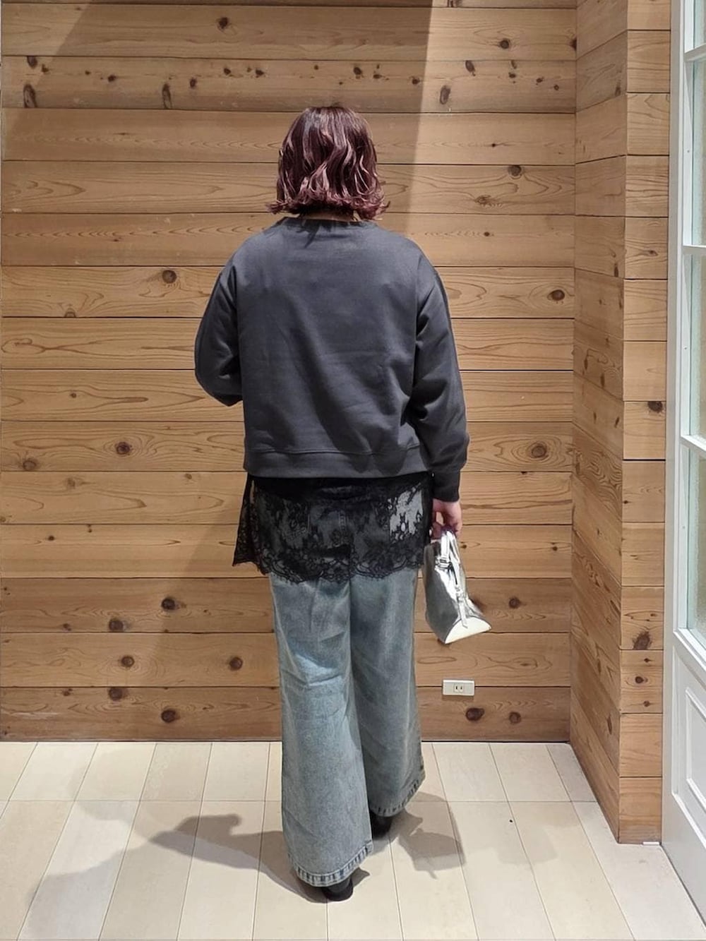 シルバー系のショルダーバッグ、ブラック系のローファー、ブルー系のデニムパンツを着用したレディースの冬コーディネートの3枚目の写真