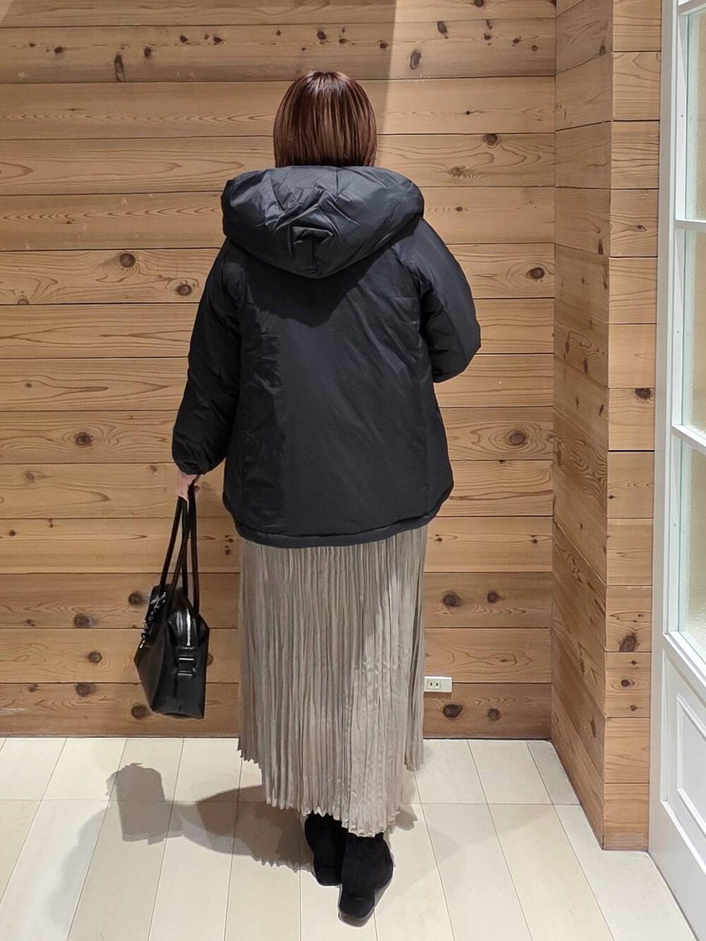 ブラック系のダウンジャケット/コート、ブラック系のボストンバッグ、ホワイト系のTシャツ/カットソーを着用したレディースの冬コーディネートの3枚目の写真