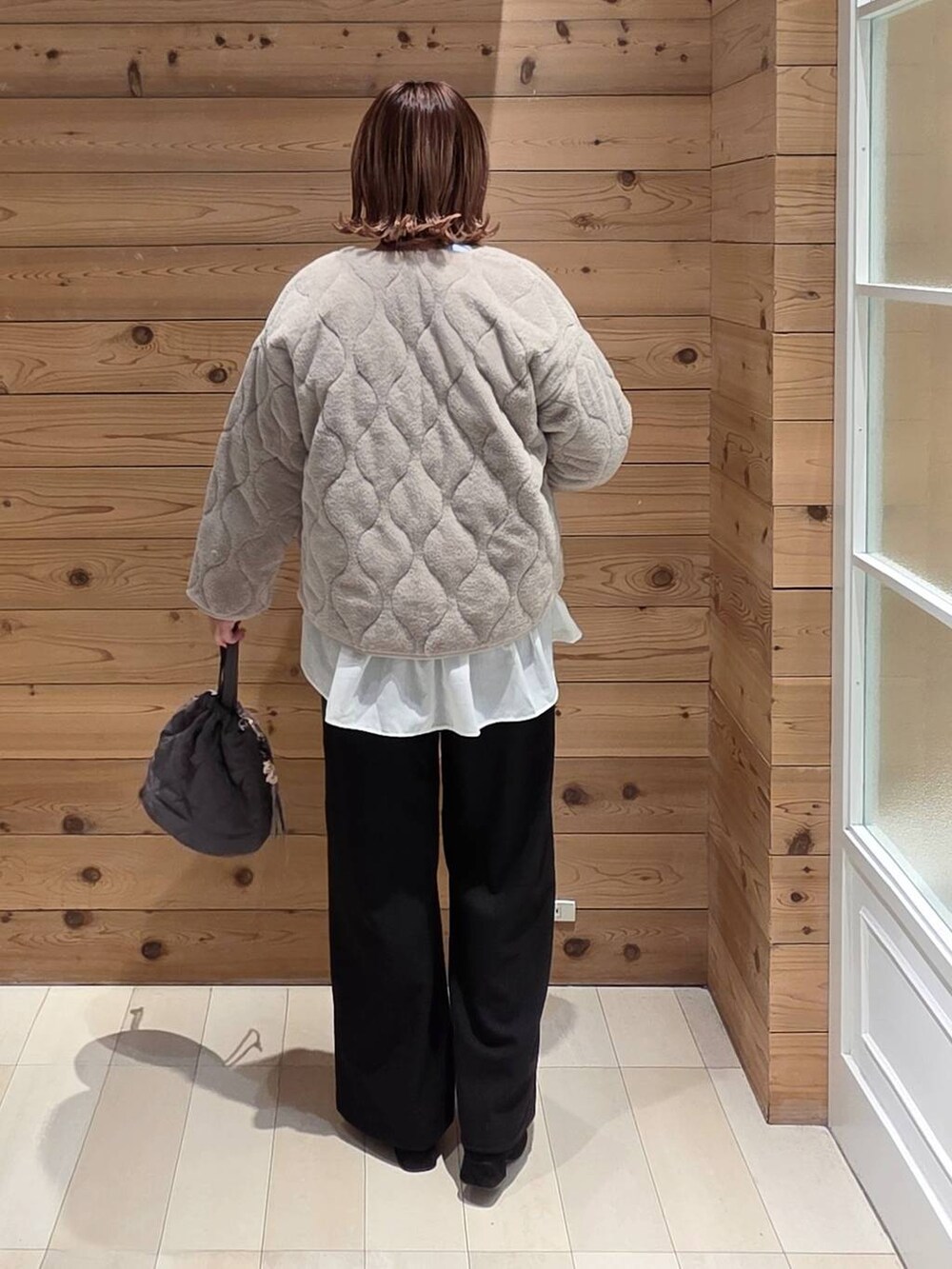 ベージュ系のブルゾン、グレー系のハンドバッグ、ブルー系のニット/セーターを着用したレディースの冬コーディネートの3枚目の写真