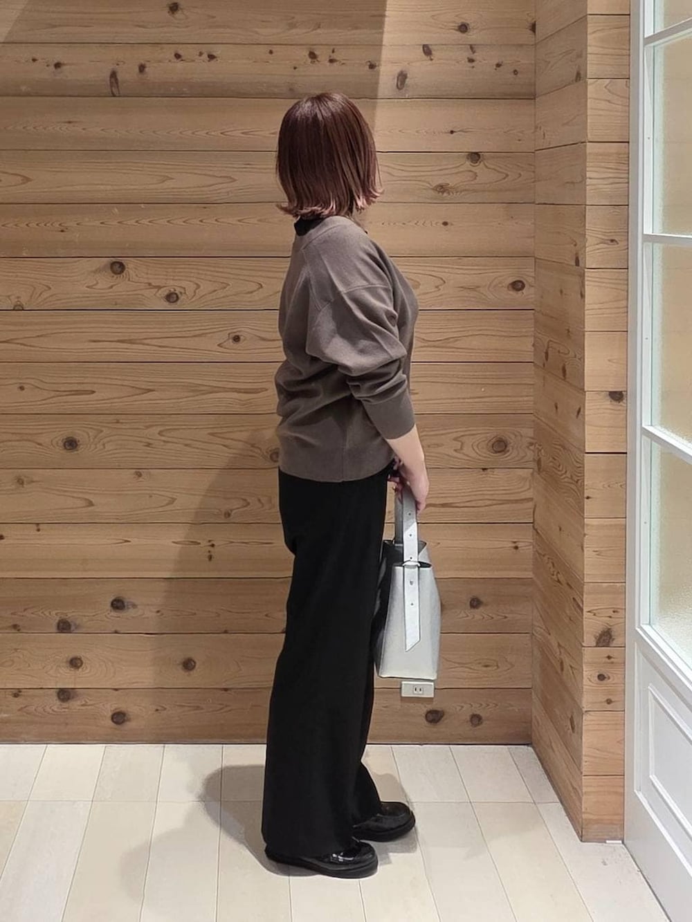 ブラック系のローファー、シルバー系のショルダーバッグ、ブラック系のスラックスを着用したレディースの春コーディネートの2枚目の写真