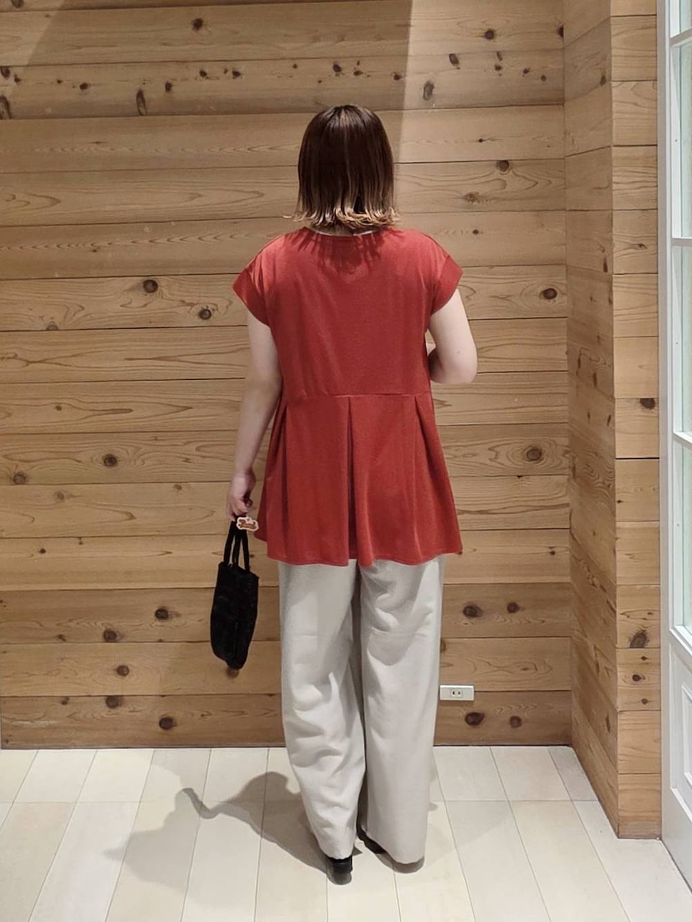 ベージュ系のその他パンツ、レッド系のTシャツ/カットソー、ブラック系のクラッチバッグを着用したレディースの夏コーディネートの3枚目の写真