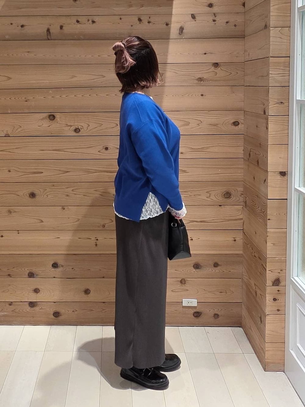 ブラック系のショルダーバッグ、ブラック系のローファー、ホワイト系のTシャツ/カットソーを着用したレディースの冬コーディネートの2枚目の写真