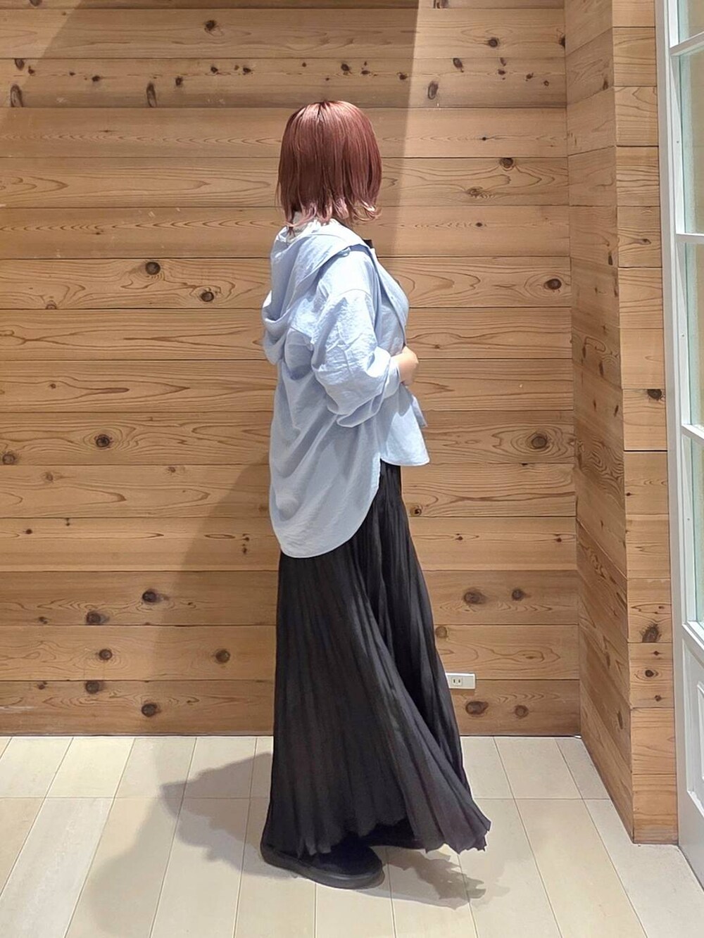 グレー系のスカート、ホワイト系のTシャツ/カットソー、ブラック系のスニーカーを着用したレディースの秋コーディネートの2枚目の写真