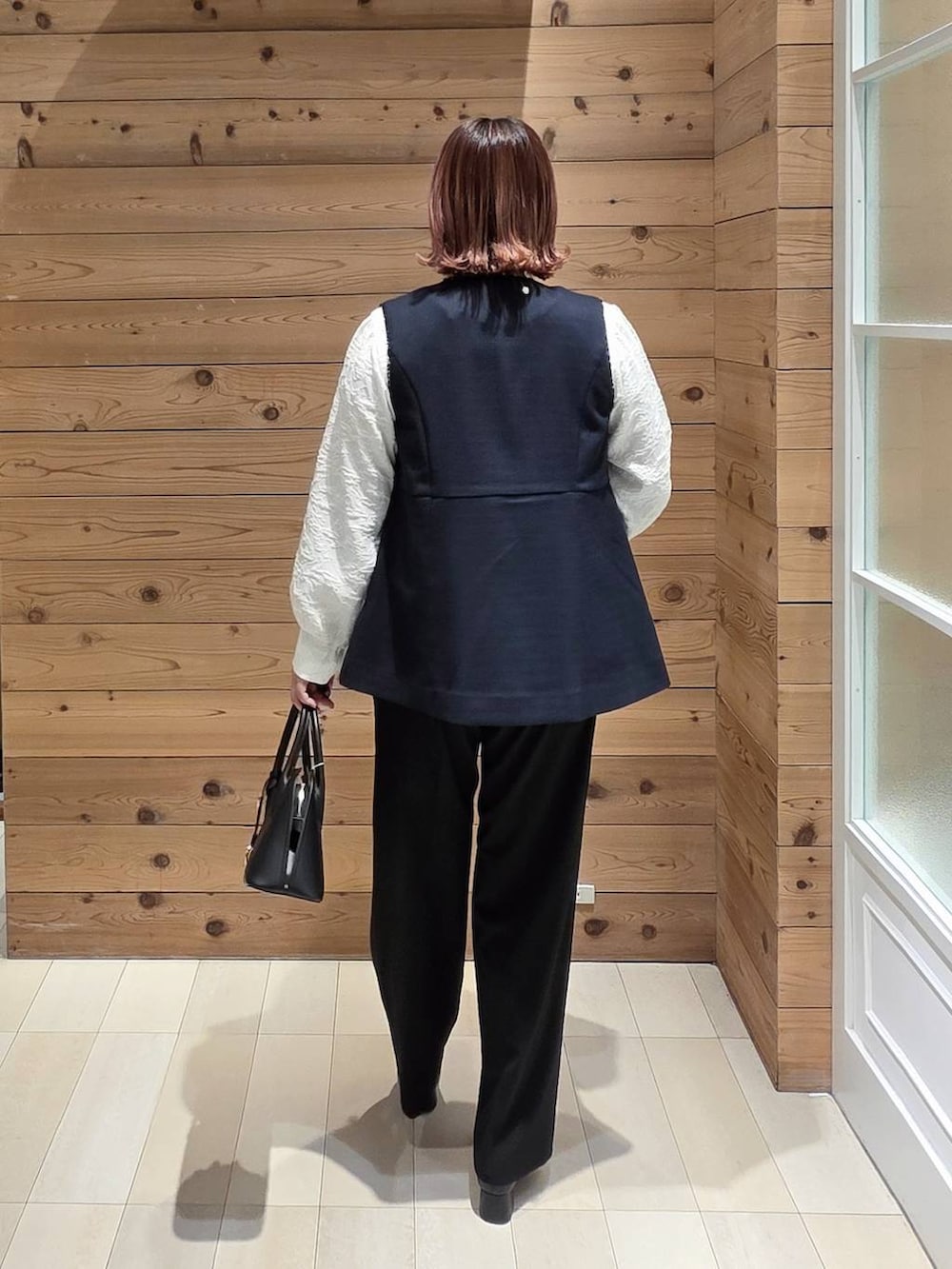 ブラック系のローファー、ブラック系のショルダーバッグ、ブラック系のスラックスを着用したレディースの冬コーディネートの3枚目の写真